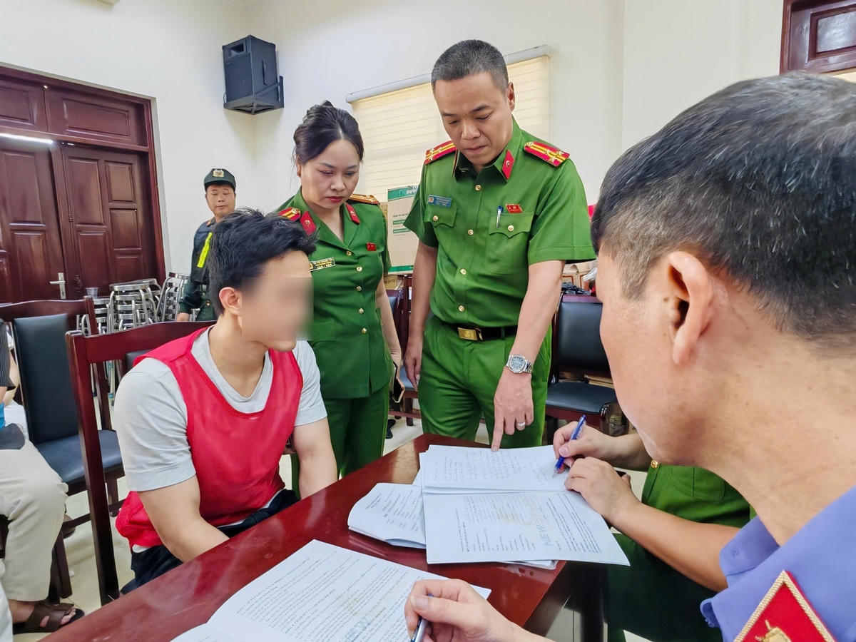Đối tượng Hoàng Nhất Long (áo đỏ), giám đốc Công ty TNHH thương mại và dịch vụ Sunland Travel khai báo với cơ quan điều tra. Ảnh: Công an TP. Hà Nội.