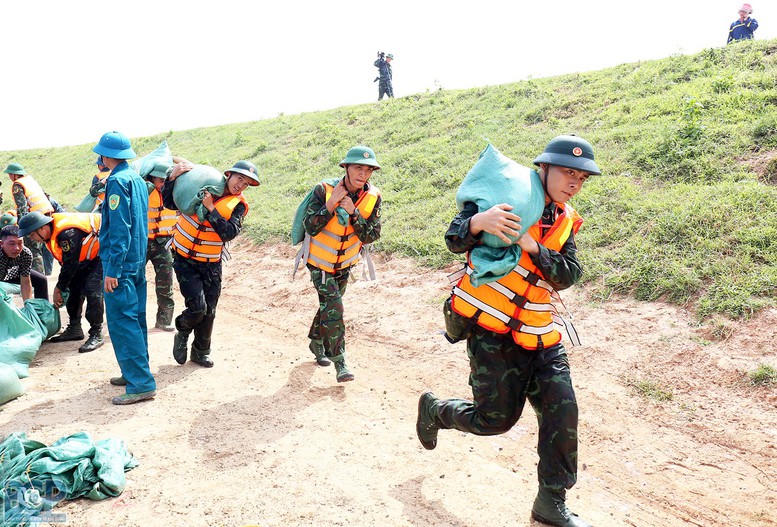 Cán bộ, chiến sĩ lực lượng vũ trang khẩn trương vận chuyển bao tải gia cố tuyến đê, ứng phó nguy cơ ngập lụt trong mùa mưa bão. Ảnh minh họa